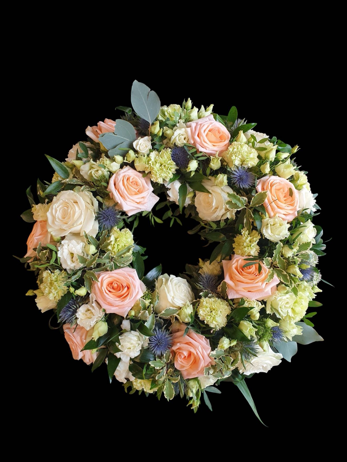 Coroană funerară elegantă cu trandafiri somon și accente albastre